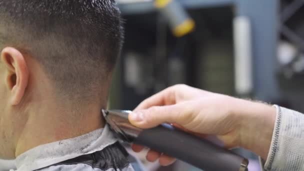 Nuca. cabeleireiro faz um corte de cabelo para um homem com um cortador de cabelo em uma barbearia — Vídeo de Stock