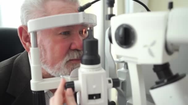 Огляд літнього чоловіка з лампою розрізу. оснащення кабінету офтальмологів . — стокове відео