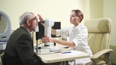 Korneo topografisi üzerine yaşlı bir adamın göz doktoru muayenesi. Modern klinik.
