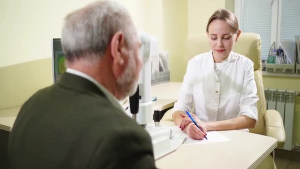 Doktor, göz hekimliği bürosunda muayene edilmeden önce yaşlılarla görüşür.. — Stok video
