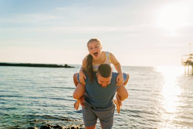 Babası deniz kıyısında kızına biniyor.. 