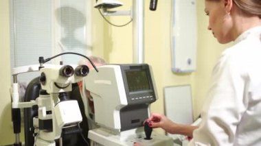 Doktor yaşlı adamları otoportafraktometre ekranında muayene ediyor.. 