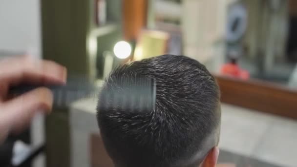 Fecha. cabeleireiro faz um corte de cabelo para um homem com uma tesoura em uma barbearia — Vídeo de Stock