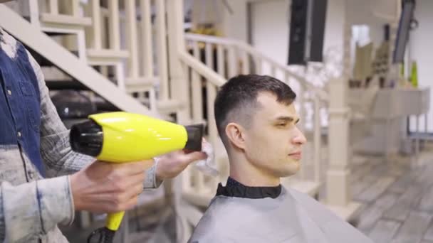 Cabeleireiro seca secador de cabelo morena homem em uma barbearia — Vídeo de Stock