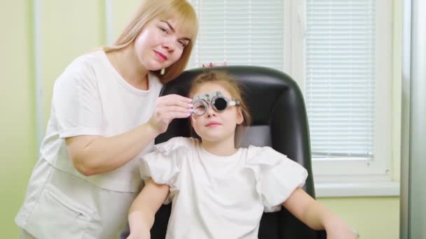 Οφθαλμίατρος διαγνώνει τα μικρά κορίτσια όραση και κάνει επιλογή των φακών. — Αρχείο Βίντεο