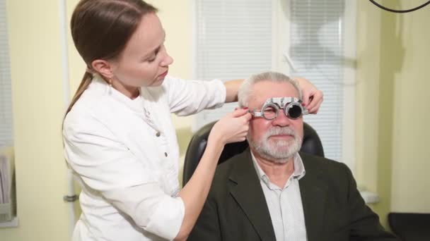 Ophtalmologiste fait une sélection de lentilles, diagnostique une vision des hommes âgés. — Video