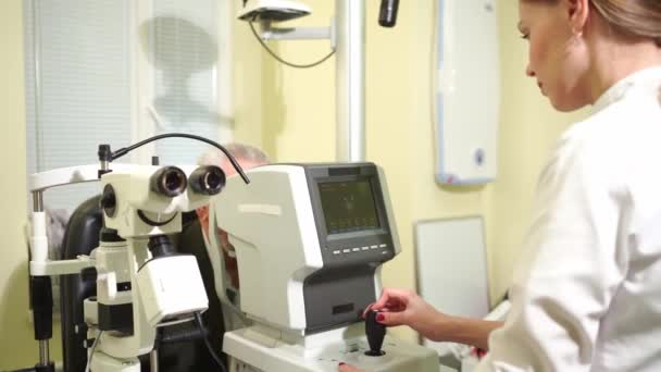 Doctor examina anciano mans ojo en pantalla de autorefractometer. — Vídeos de Stock