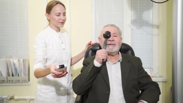 Augenarzt diagnostiziert Sehvermögen älterer Menschen auf einem Schilderprojektor. — Stockvideo