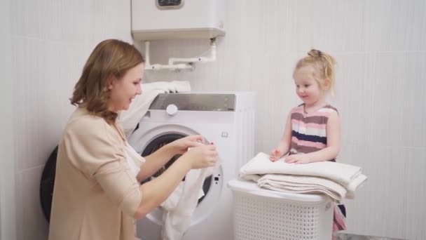 Mamma och dotter vika tvätt efter tvätt i tvättmaskinen. — Stockvideo