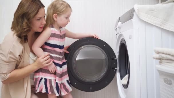 Mother and daughter open the washing machine and take out the laundry — Stock Video