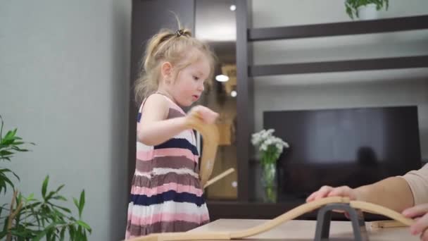 Menina brinca com brinquedo ferroviário de madeira. — Vídeo de Stock