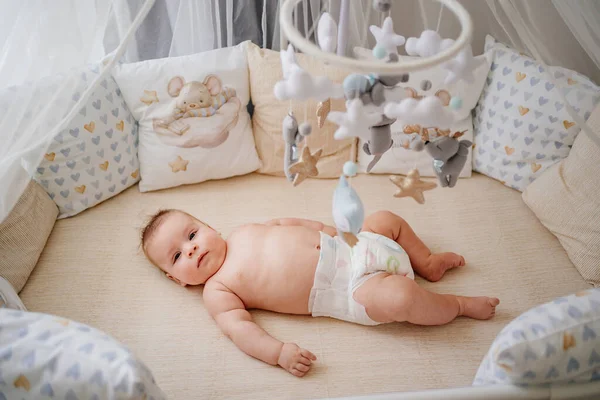 View from above. a baby lies in a white crib with mobile with toys. — Φωτογραφία Αρχείου