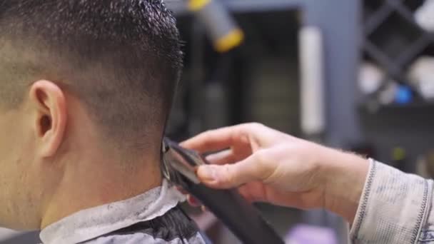 Nuca. cabeleireiro faz um corte de cabelo para um homem com um cortador de cabelo em uma barbearia — Vídeo de Stock