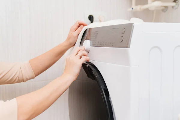 Una mujer enciende la lavadora. — Foto de Stock