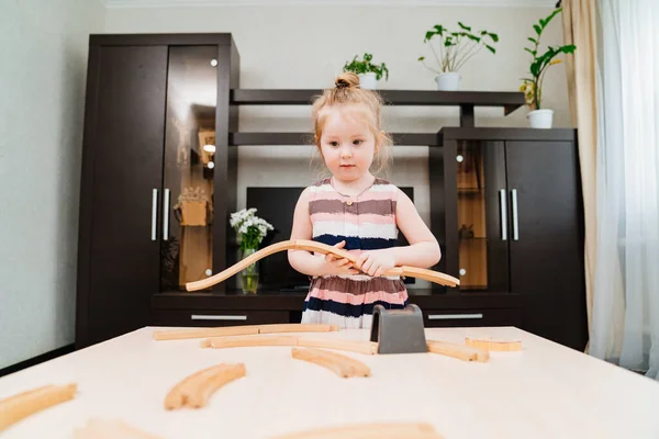 Dziewczynka bawi się drewnianą koleją zabawek. — Zdjęcie stockowe