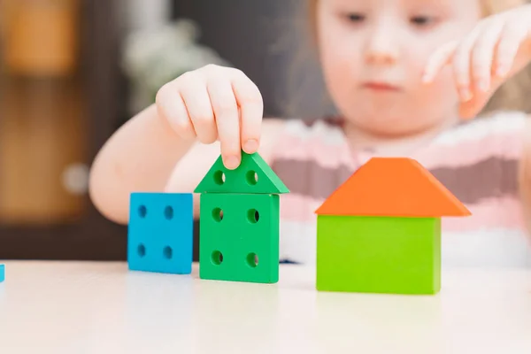 Cute little girl buduje domy z kolorowego drewnianego zestawu budowlanego. — Zdjęcie stockowe