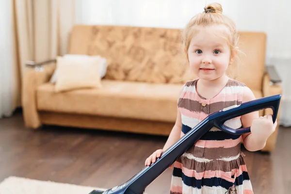 Linda niña limpia independientemente la alfombra en la habitación con aspiradora — Foto de Stock