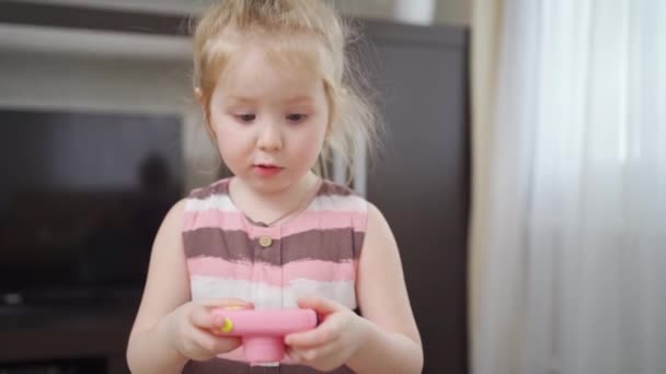 Смішна маленька дівчинка робить фото на маленькій рожевій іграшковій камері . — стокове відео