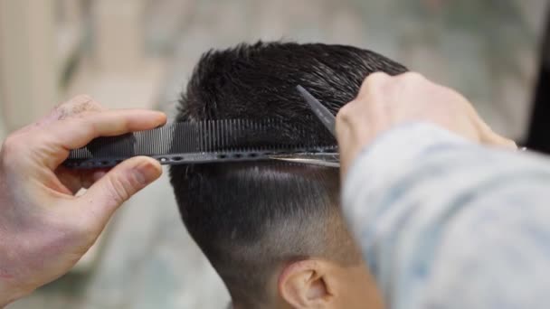 Fecha. cabeleireiro faz um corte de cabelo para um homem com uma tesoura em uma barbearia — Vídeo de Stock