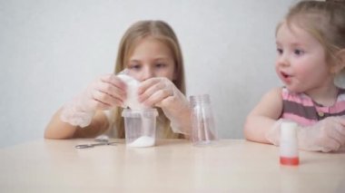Koruyucu eldivenli şirin küçük kızlar evde bir deney yapıyorlar. 