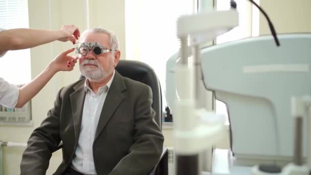 Okulista diagnozuje widzenie starszych mężczyzn i dokonuje wyboru soczewek. — Wideo stockowe