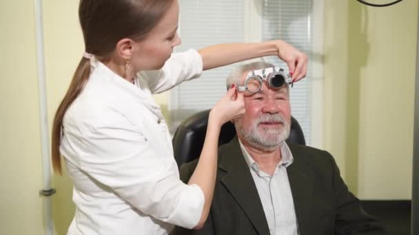 Göz doktoru mercek seçimi yapar, yaşlı bir adamın görüşünü teşhis eder.. — Stok video