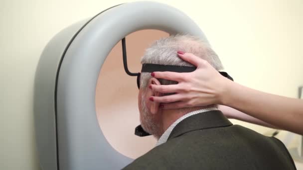 Examination of elderly man on on device pnr the perimeter of the field of view — Stock Video