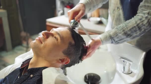 Seorang pria kulit coklat mencuci rambut dengan penata rambut di sebuah salon. — Stok Video