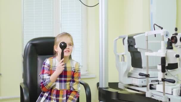 Un oftalmólogo diagnostica la visión de una niña en un proyector de señales. — Vídeos de Stock