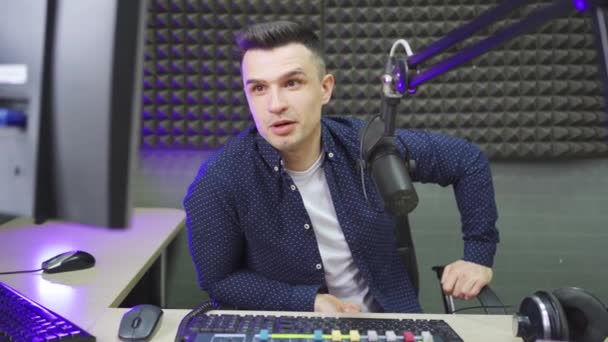 Um apresentador de rádio masculino realiza uma transmissão ao vivo em um estúdio de rádio profissional. — Vídeo de Stock