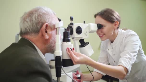 Огляд офтальмолога літнього чоловіка з лампою розрізу. медичне обладнання — стокове відео