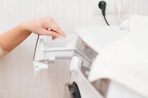 Uma mulher coloca detergente de roupa na máquina de lavar roupa — Fotografia de Stock