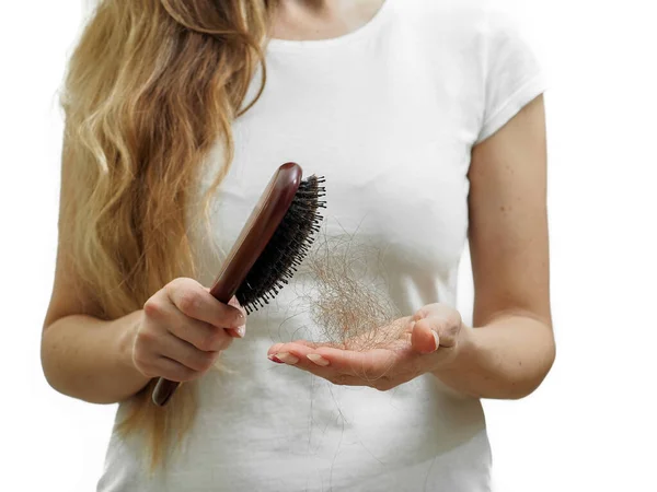 Una chica con el pelo largo y rubio sostiene un peine y la pérdida de cabello en sus manos. El problema de la alopecia — Foto de Stock