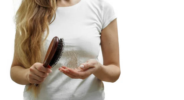 Una chica con el pelo largo y rubio sostiene un peine y la pérdida de cabello en sus manos. El problema de la alopecia — Foto de Stock