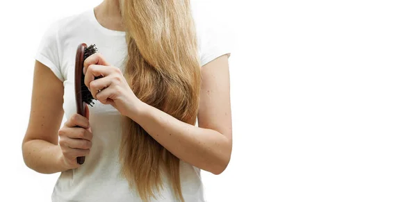 Una chica con el pelo largo y rubio sostiene un peine y la pérdida de cabello en sus manos. El problema de la alopecia —  Fotos de Stock