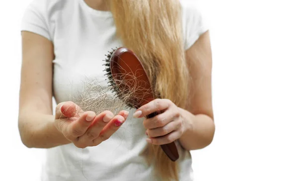Una chica con el pelo largo y rubio sostiene un peine y la pérdida de cabello en sus manos. El problema de la alopecia —  Fotos de Stock