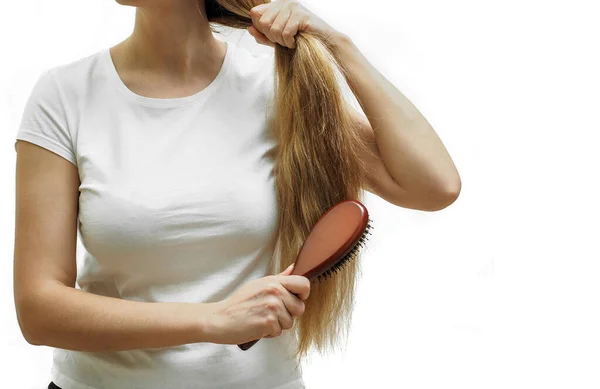 A girl with long blonde hair combs them with a comb The problem of alopecia and hair loss, hair care — Stock Photo, Image