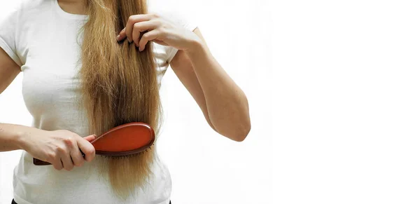 Una chica con el pelo largo y rubio los peina con un peine El problema de la alopecia y la caída del cabello, el cuidado del cabello — Foto de Stock