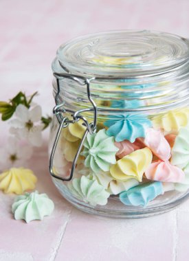 Cam kavanozda pembe fayansların üzerinde küçük renkli kremalar var.