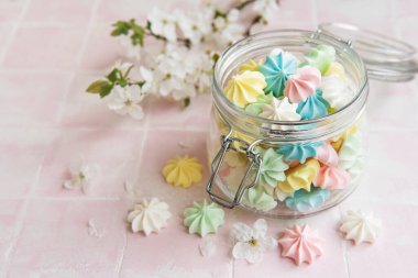 Cam kavanozda pembe fayansların üzerinde küçük renkli kremalar var.