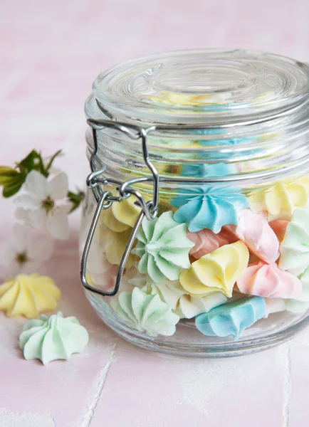 Cam kavanozda pembe fayansların üzerinde küçük renkli kremalar var.