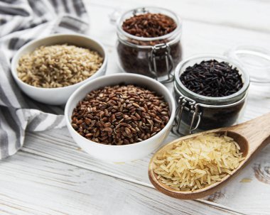 Beyaz ahşap zemin üzerinde çeşitli pirinç seti: siyah, basmati, kahverengi ve kırmızı karışık pirinç