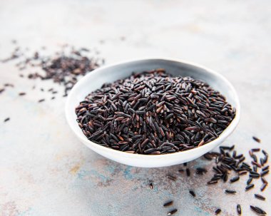 Gri bir zeminde pişmemiş bir kase yabani pirinç.