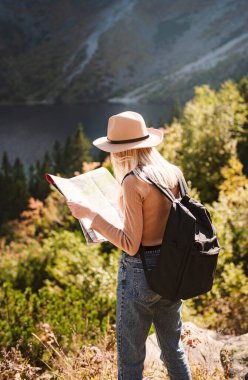 Şapka takan ve muhteşem dağlara ve göle bakan seyahat tutkusu konsepti olan kadın gezgin. Polonya Tatralarında Morskoy Gölü Gözü.