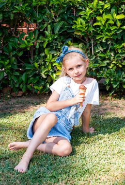 Küçük kız dışarıda çikolatalı dondurma yiyor.