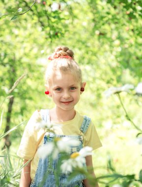 Şirin küçük kız kiraz bahçesindeki bir ağaçtan kiraz topluyor.
