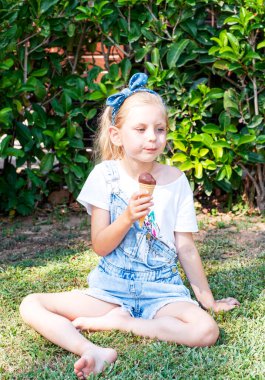 Küçük kız dışarıda çikolatalı dondurma yiyor.