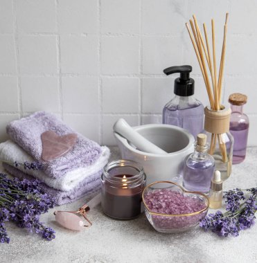 Lavanta kaplıcası. Gerekli yağlar, deniz tuzu, havlular ve yüz silindiri. Lavanta çiçekli doğal bitki kozmetiği.