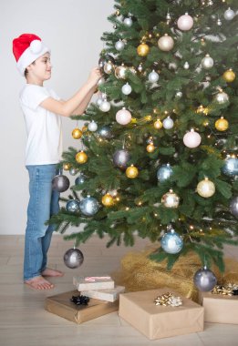 Hediyeli çocuk Noel ağacının yanında oynuyor. Oturma odasının içi Noel ağacı ve süslemelerle dolu. Yeni yıl. Hediye vermek.