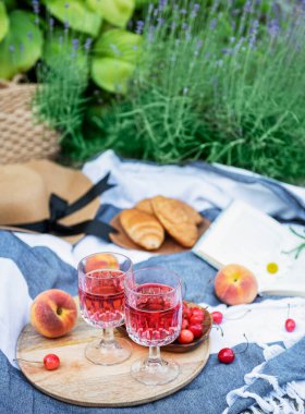 Lavanta tarlalarında piknik. Bardakta gül şarabı, battaniyede kiraz ve hasır şapka